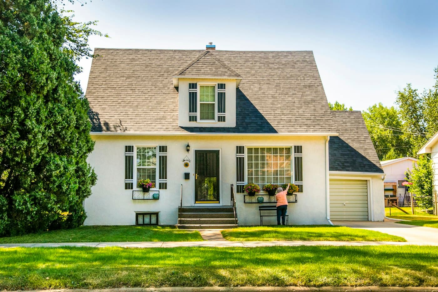 A white family home with a green lawn on a sunny day
