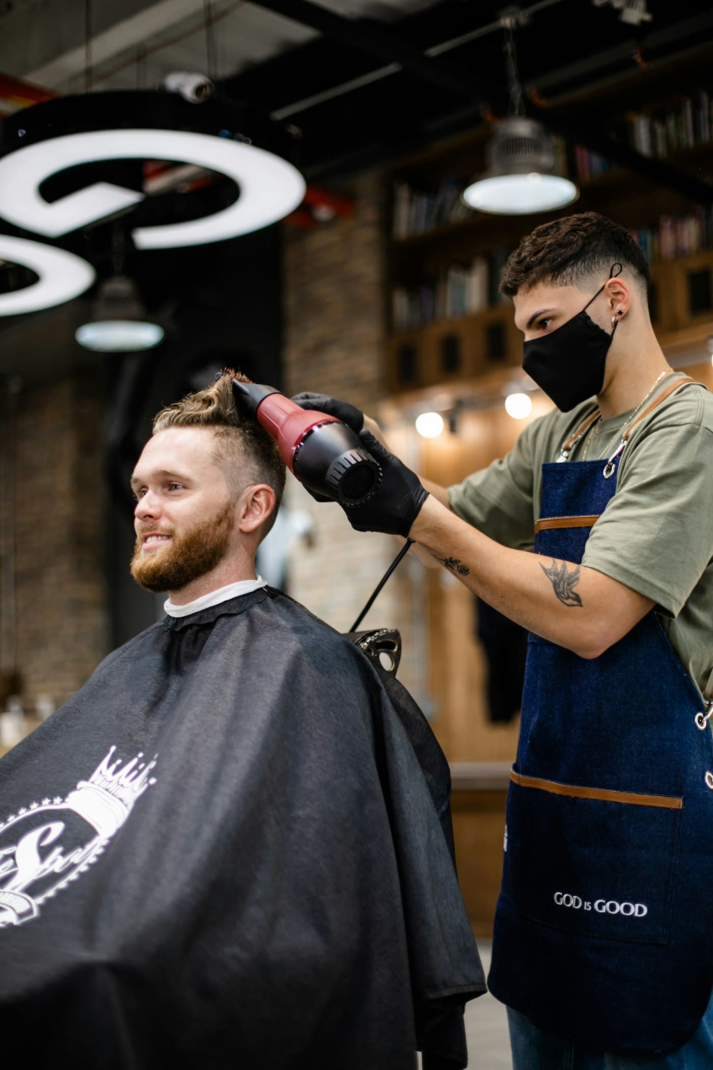 A stylist blow-drying a smiling client's hair in a salon